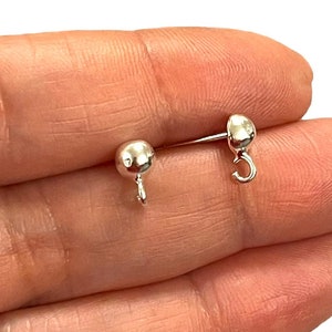 Peut inclure: Deux dos d'oreille en argent avec une petite boule à une extrémité et un crochet à l'autre.