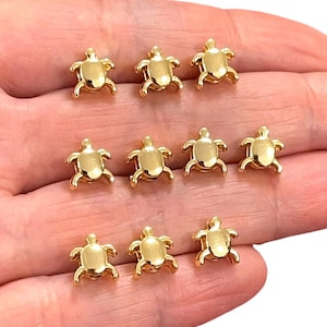 May include: Ten gold-colored turtle charms. The charms are small and detailed, with a realistic turtle design.