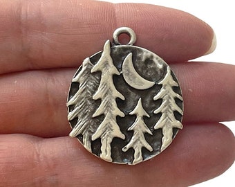 May include: Silver charm with a textured circular design featuring a crescent moon and five pine trees.