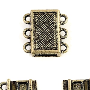 May include: Three antique gold-toned metal clasps for necklaces or bracelets. Each clasp has four loops and a decorative design.