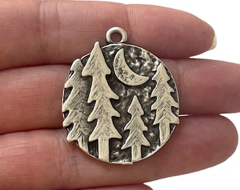 May include: Silver charm with a textured circular design featuring a crescent moon and four stylised pine trees.