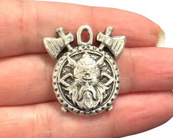 May include: Silver pendant charm featuring a Viking warrior's face with a beard, helmet, and crossed axes.