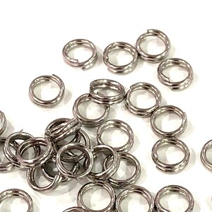 May include: A pile of silver jump rings, a type of jewelry finding used for connecting chains, cords, and other jewelry components.