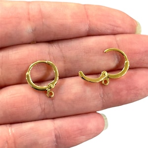 Peut inclure: Deux créoles d'oreille dorées avec une fermeture à ressort. Chaque créole a une petite boucle en bas.