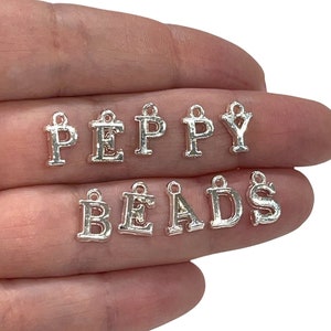 May include: Silver letter charms spelling out the words "PEPPY BEADS".