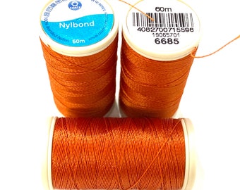 May include: Three spools of orange thread, each with a white label that reads "Nylbond 60m" and a barcode. The label on the top spool also has the text "4082700715596 19085701 6685".