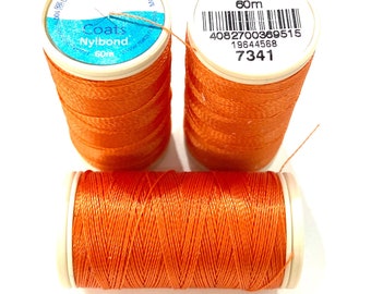 May include: Three spools of orange Coats Nybond thread. The spools are labeled with the brand name, thread type, and length. The spools are 60m long.