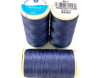 May include: Three spools of navy blue Nylbond thread are displayed against a white background. Two spools are upright, and one is horizontal. The spools have white labels with blue text, including the brand name and the measurement of 60m.