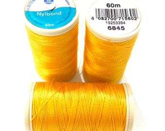 May include: Three spools of bright yellow Nylbond thread, each with a white label. The labels display the brand name, thread type, and length of 60m. The spools are arranged on a white surface.