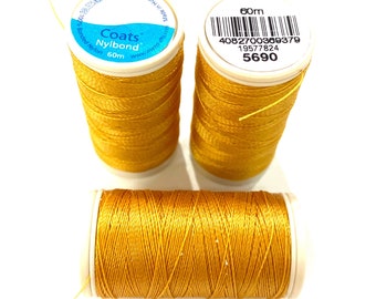 May include: Three spools of golden-yellow Coats Nylbond thread, 60m each, are displayed against a white background. The thread is tightly wound on white spools, with the brand name and product details visible on the labels.
