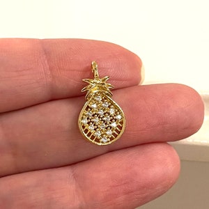 Puede incluir: Encanto de piña de oro con piedras de circonita cúbica transparentes. El encanto mide aproximadamente 2,5 cm de alto y tiene un bucle en la parte superior para sujetarlo a un collar o pulsera.