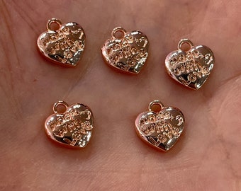 Puede incluir: Cinco dijes de corazón de tono dorado con las palabras "Made with Love" grabadas en ellos.