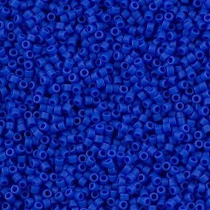 Może przedstawiać: Zbliżenie na dużą ilość małych, okrągłych, nieprzezroczystych, niebieskich koralików. Koraliki są jednolite pod względem rozmiaru i kształtu i są ułożone w losowym wzorze.