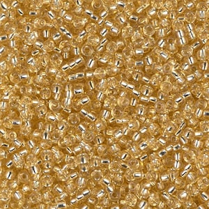 May include: A close-up of a large quantity of small, gold-coloured glass beads. The beads are round and have a metallic sheen.