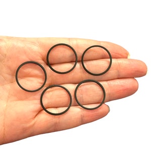 May include: Six black rubber rings, probably for a watch or other small object.