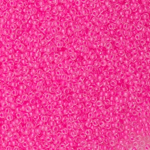 May include: A close-up image of a large quantity of small, round, pink beads. The beads are translucent and have a slight shimmer.