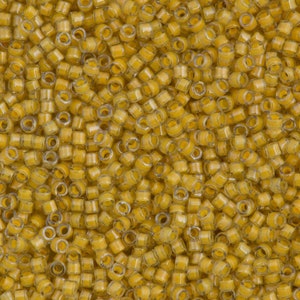 May include: A close-up image of a large quantity of small, round, transparent glass beads. The beads are a light yellow colour and have a slight shimmer to them.