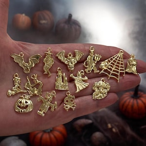 Puede incluir: Una colección de 15 abalorios de Halloween de metal dorado con varios diseños espeluznantes, que incluyen un murciélago, un fantasma, una telaraña, una calabaza y una calavera.
