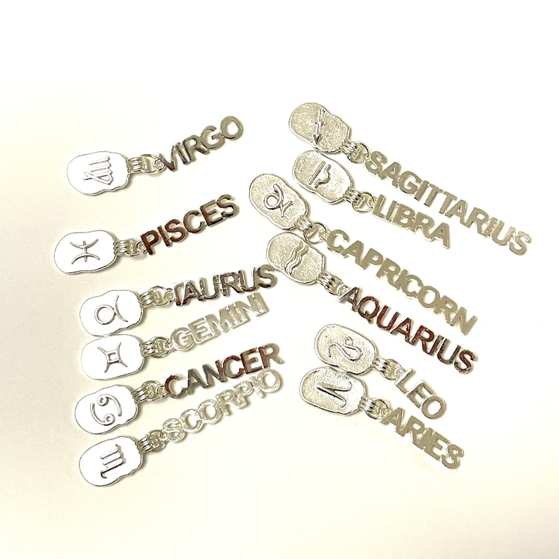 May include: Silver charms with the zodiac signs and names: Aries, Taurus, Gemini, Cancer, Leo, Virgo, Libra, Scorpio, Sagittarius, Capricorn, Aquarius, and Pisces.