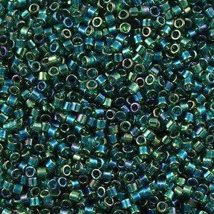 Könnte beinhalten: Nahaufnahme einer großen Menge kleiner, runder, blaugrüner Glasperlen. Die Perlen haben einen metallischen Glanz und sind in einem zufälligen Muster angeordnet.