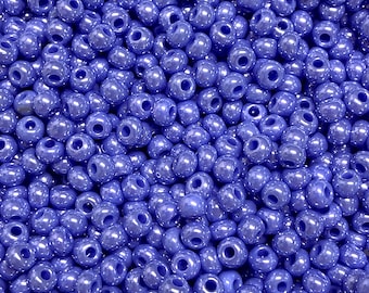 Può includere: Una vista ravvicinata di una grande quantità di piccole perline rotonde di vetro blu. Le perline hanno una finitura leggermente iridescente, che conferisce loro un leggero bagliore.