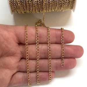 Puede incluir: Cadena de oro, un primer plano de una cadena de oro en una mano. La cadena es fina y delicada, y es perfecta para hacer joyas.