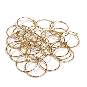 May include: A pile of gold-colored hoop earrings. The earrings are small and delicate, and they are perfect for adding a touch of sparkle to any outfit.