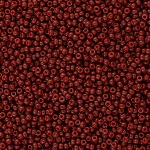 Puede incluir: Una imagen de primer plano de una gran cantidad de pequeñas cuentas redondas de color rojo oscuro. Las cuentas son todas del mismo tamaño y forma, y están dispuestas en un patrón aleatorio.