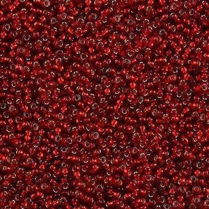 Puede incluir: Primer plano de un montón de pequeñas cuentas de semillas rojas. Las cuentas están densamente empaquetadas, creando una superficie texturizada. Cada cuenta tiene un pequeño agujero en el centro. Las cuentas tienen una calidad brillante y reflectante.