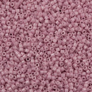 Può includere: Un'immagine ravvicinata di una grande quantità di piccole perline rotonde di colore rosa chiaro. Le perline sono opache e hanno una finitura leggermente iridescente.