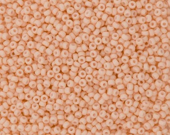 May include: A close-up view of a large quantity of small, round, peach-colored beads. The beads are all the same size and shape, and they are arranged in a random pattern.