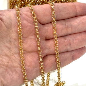 Könnte beinhalten: Goldkette mit einem zarten, runden Gliederdesign. Die Kette wird in einer Hand gezeigt, wodurch ihre Länge und Textur hervorgehoben werden.