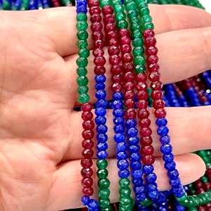 May include: A strand of faceted gemstone beads in red, green, and blue. The beads are strung on a clear thread and are ready for jewellery making.