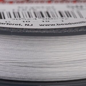 May include: Close-up of a spool of clear, fine beading thread. The thread is tightly wound on a gray spool. The label shows a barcode and text including "Carteret, NJ" and "www.beadsmith.com".