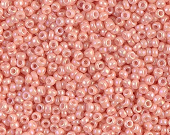 May include: A close-up view of a large quantity of small, round, iridescent pink beads. The beads have a smooth, glossy finish and are perfect for jewelry making or other craft projects.