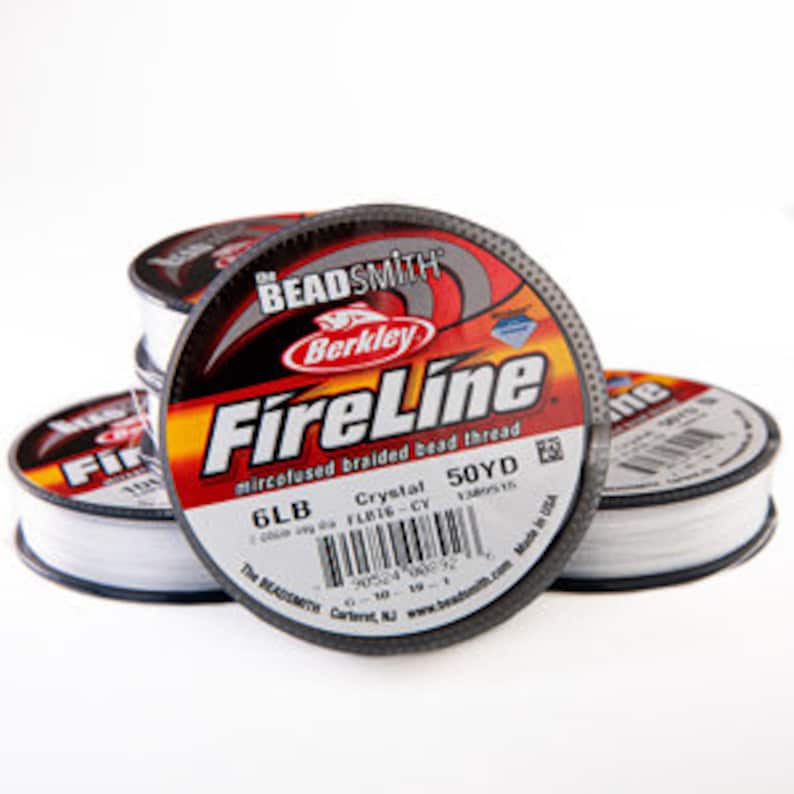 May include: Several spools of Berkley FireLine microfused braided bead thread are stacked. The spools are black and white with red and yellow accents. The label reads "FireLine" and "6LB" with a barcode.
