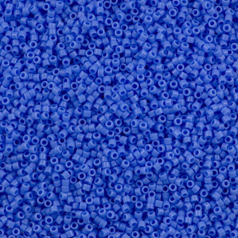 May include: A close-up view of a large quantity of small, round, blue beads. The beads are all the same size and shape, and they are arranged in a random pattern.