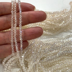 May include: A strand of iridescent clear glass beads. The beads are small and round, and they have a subtle sparkle.