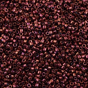 Può includere: Un'immagine ravvicinata di una grande quantità di piccole perline rotonde e metalliche. Le perline sono di colore bordeaux scuro con un effetto metallizzato.
