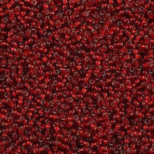 Pode incluir: Uma vista de perto de uma pilha de pequenas contas redondas vermelhas. As contas têm uma qualidade translúcida, com uma pitada de ouro ou cor clara visível dentro de cada conta. As contas estão densamente embaladas, criando uma superfície texturizada.