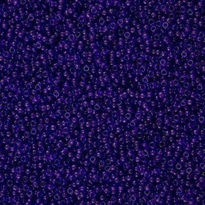 May include: A close-up image of a large quantity of small, round, purple glass beads. The beads are opaque and have a slight sheen.
