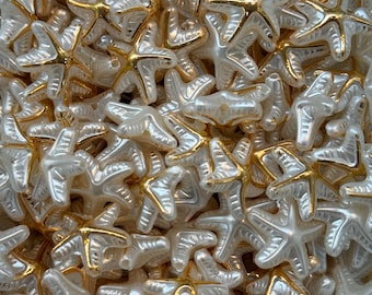 May include: A collection of pearlescent white starfish beads with gold-colored accents. The beads are five-pointed and have a glossy finish. These decorative beads are ideal for jewelry making, crafting, or adding a nautical touch to various projects.