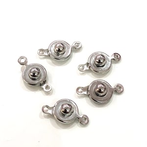 May include: Five silver-toned metal clasps with a round ball in the center. Each clasp has two loops on either side.
