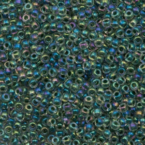 May include: A close-up view of a large quantity of small, round, iridescent teal glass beads. The beads have a slightly translucent quality and are perfect for jewelry making or crafting.
