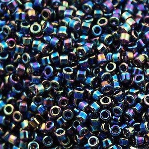 Può includere: Una vista ravvicinata di una grande quantità di piccole perline rotonde e iridescenti. Le perline sono un mix di colori blu, viola e verde, creando un effetto scintillante.