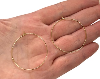 May include: A pair of gold hoop earrings. The earrings are thin and have a simple design.