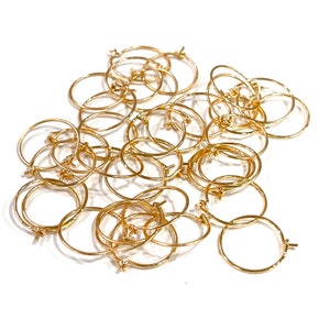 May include: A pile of gold-coloured metal hoops. The hoops are small and have a simple design.