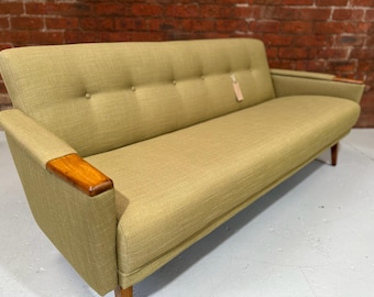 May include: A green fabric sofa with wooden arms and legs. The sofa has a tufted back and seat.