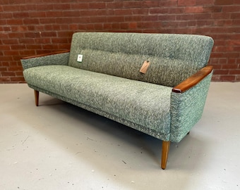 May include: A green patterned sofa with wooden arms and legs. The sofa has a tufted back and is in good condition.