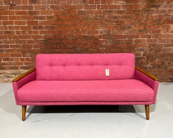 May include: A pink fabric sofa with wooden arms and legs. The sofa has a button tufted design and a price tag attached to the back.